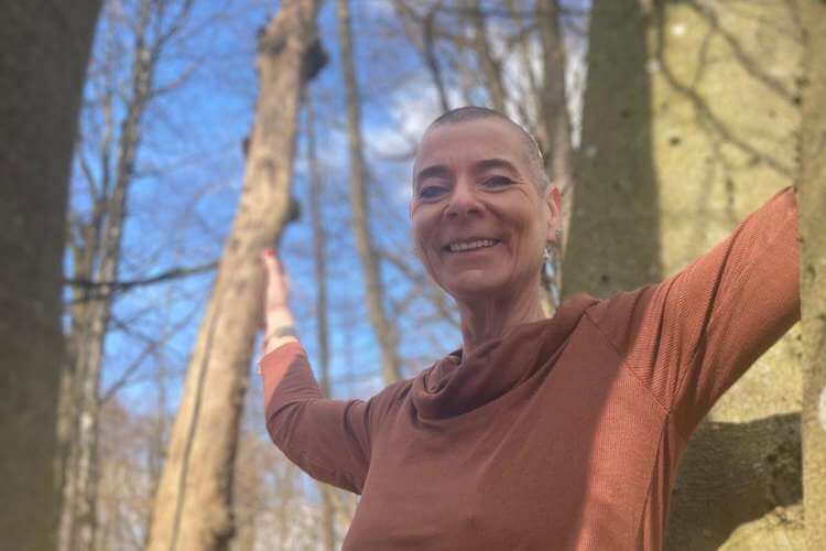 Heilpraktikern Kati Bartlau zwischen Bäumen stehend in der Natur